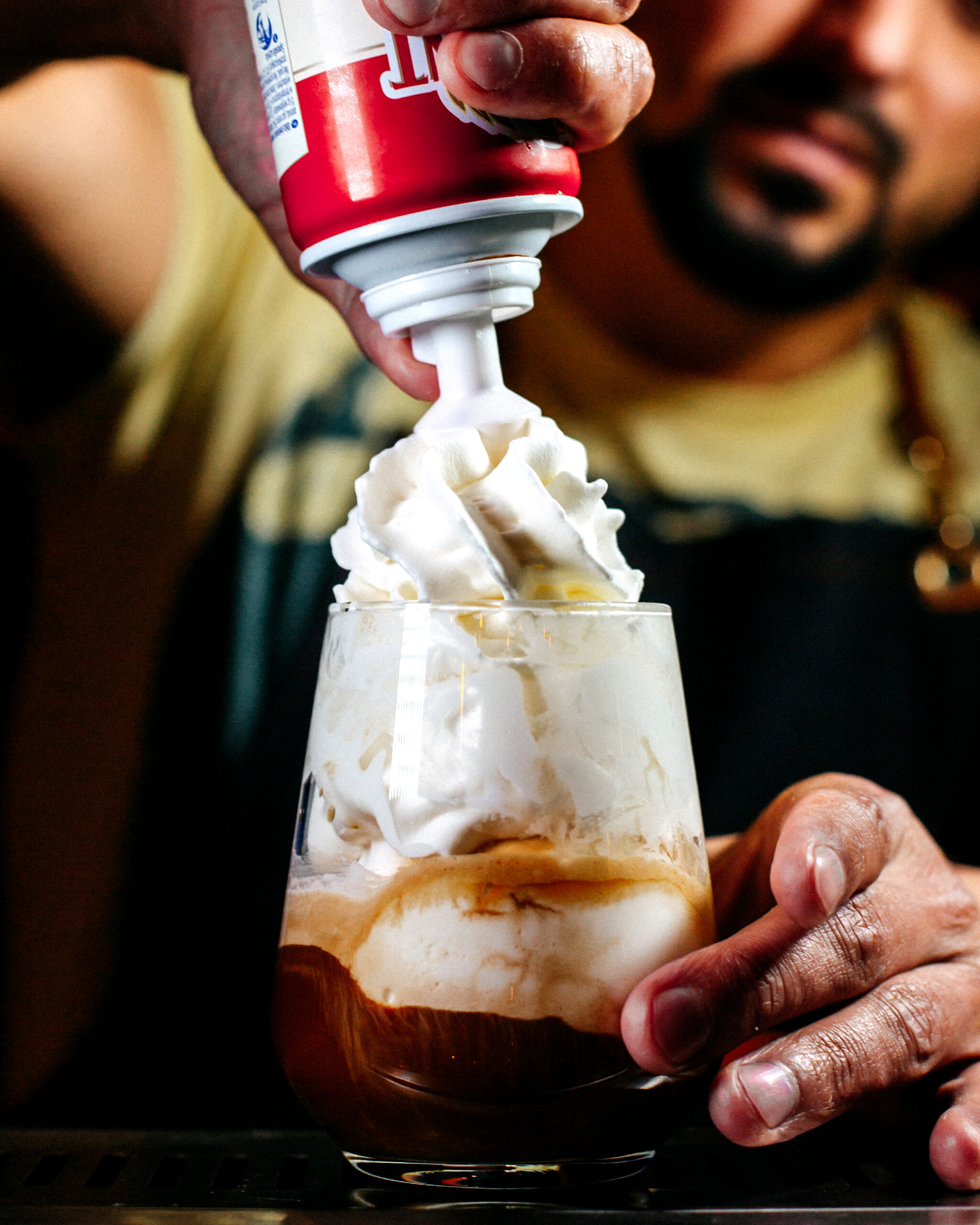 front-view-bartender-preparing-dessert-with-whipped-cream